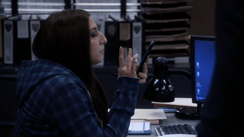 GIF of Gina Linetti (Brooklyn 99) scrolling on her phone, ignoring everything and everyone else.