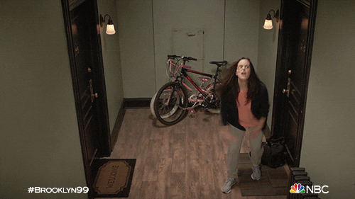 GIF of Amy Santiago (Brooklyn 99) doing a celebratory dance in a hallway.